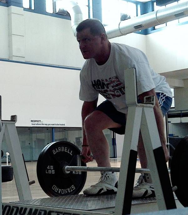 A man squatting down with a barbell that says barbell on it