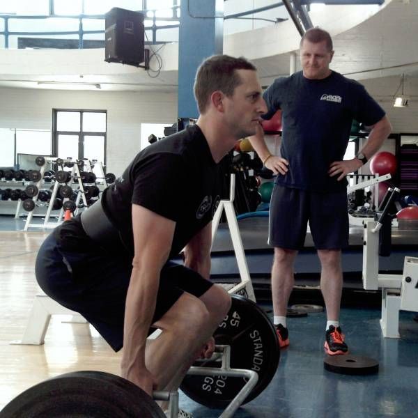 A man squatting with a barbell that says ' sland ' on it