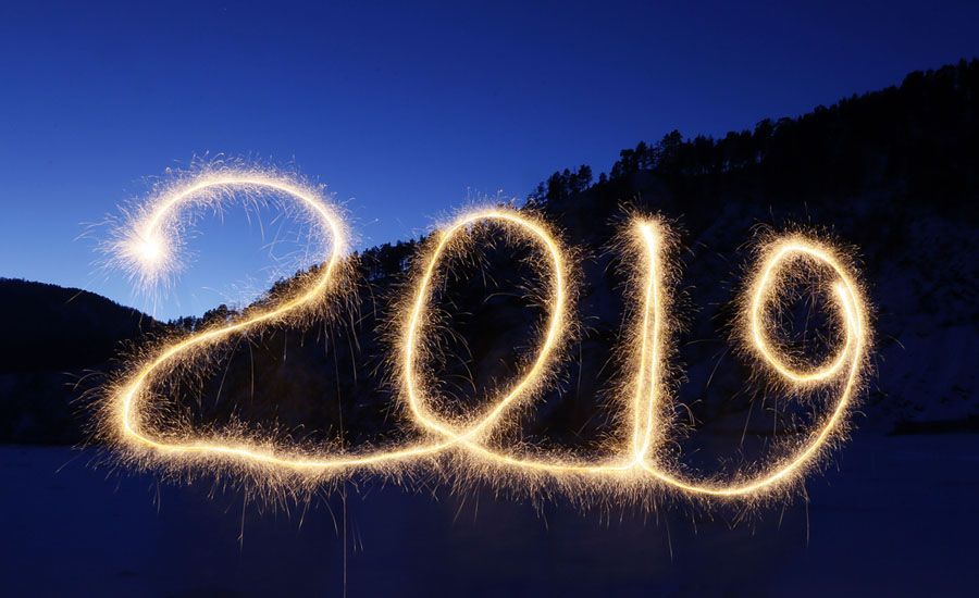 The year 2019 is written with sparklers in the snow.