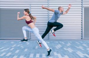 A man and a woman are jumping in the air while running.