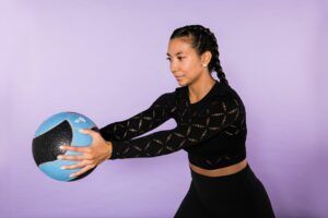 A woman is holding a blue ball in her hands.