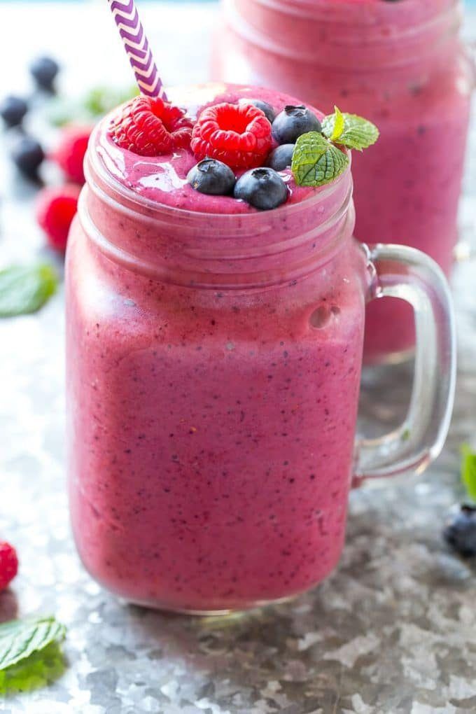 A smoothie in a mason jar with raspberries and blueberries on top.