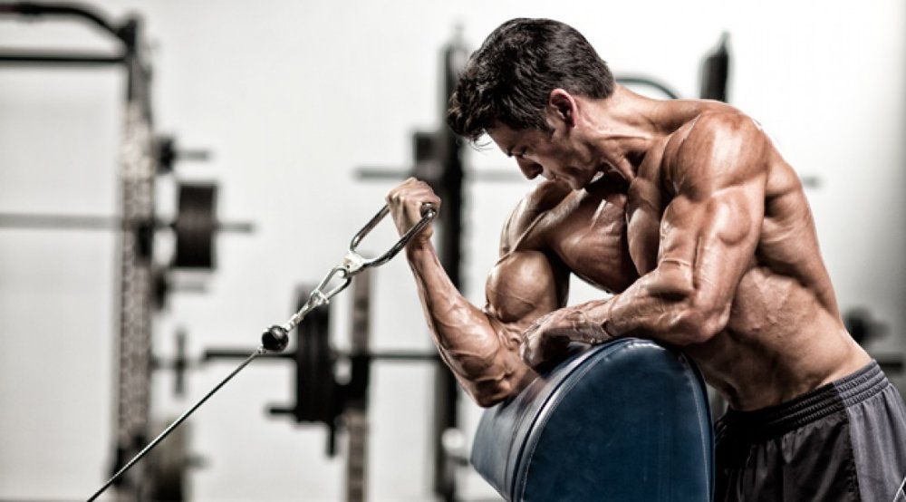 A shirtless man is lifting a barbell in a gym.