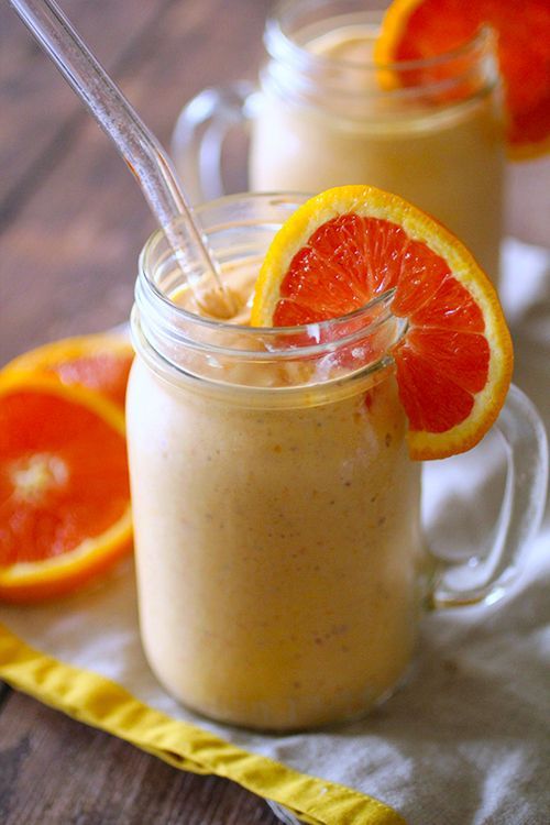 A close up of a smoothie in a mason jar with a straw and grapefruit slices.