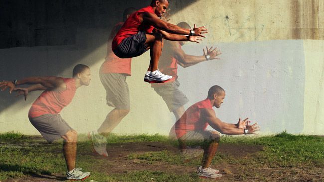 A man is jumping in the air while squatting in the grass.