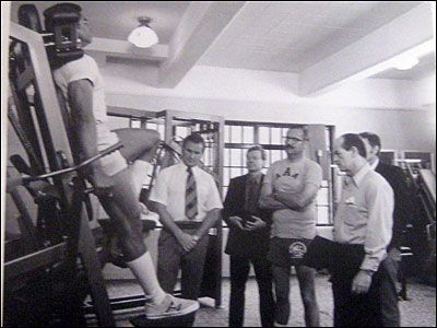 A black and white photo of a man doing exercises in a gym