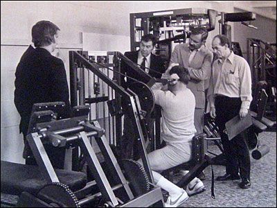 A group of men are looking at a machine in a gym