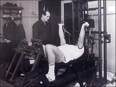 A black and white photo of a man lifting weights in a gym