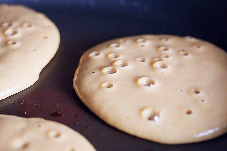 Three pancakes are being cooked in a frying pan