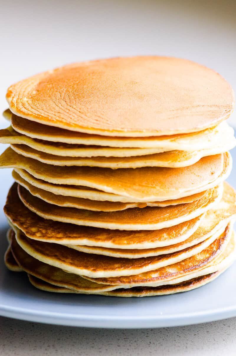 A stack of pancakes on a blue plate on a table.