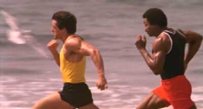 Two men are running on the beach near the water.