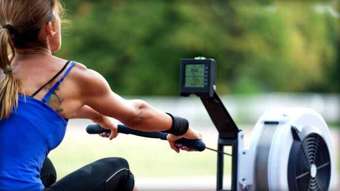 A woman is riding a rowing machine outside.