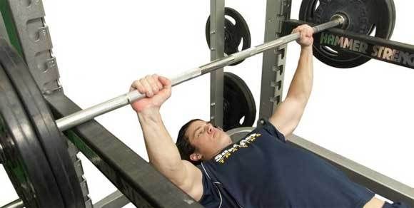 A man is laying on a bench lifting a barbell.