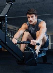 A man is riding a rowing machine in a gym.