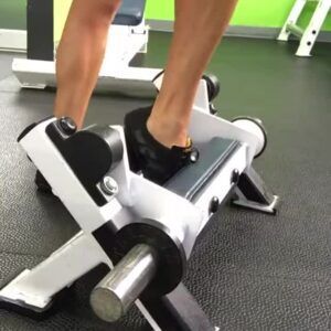 A person is standing on a machine in a gym.