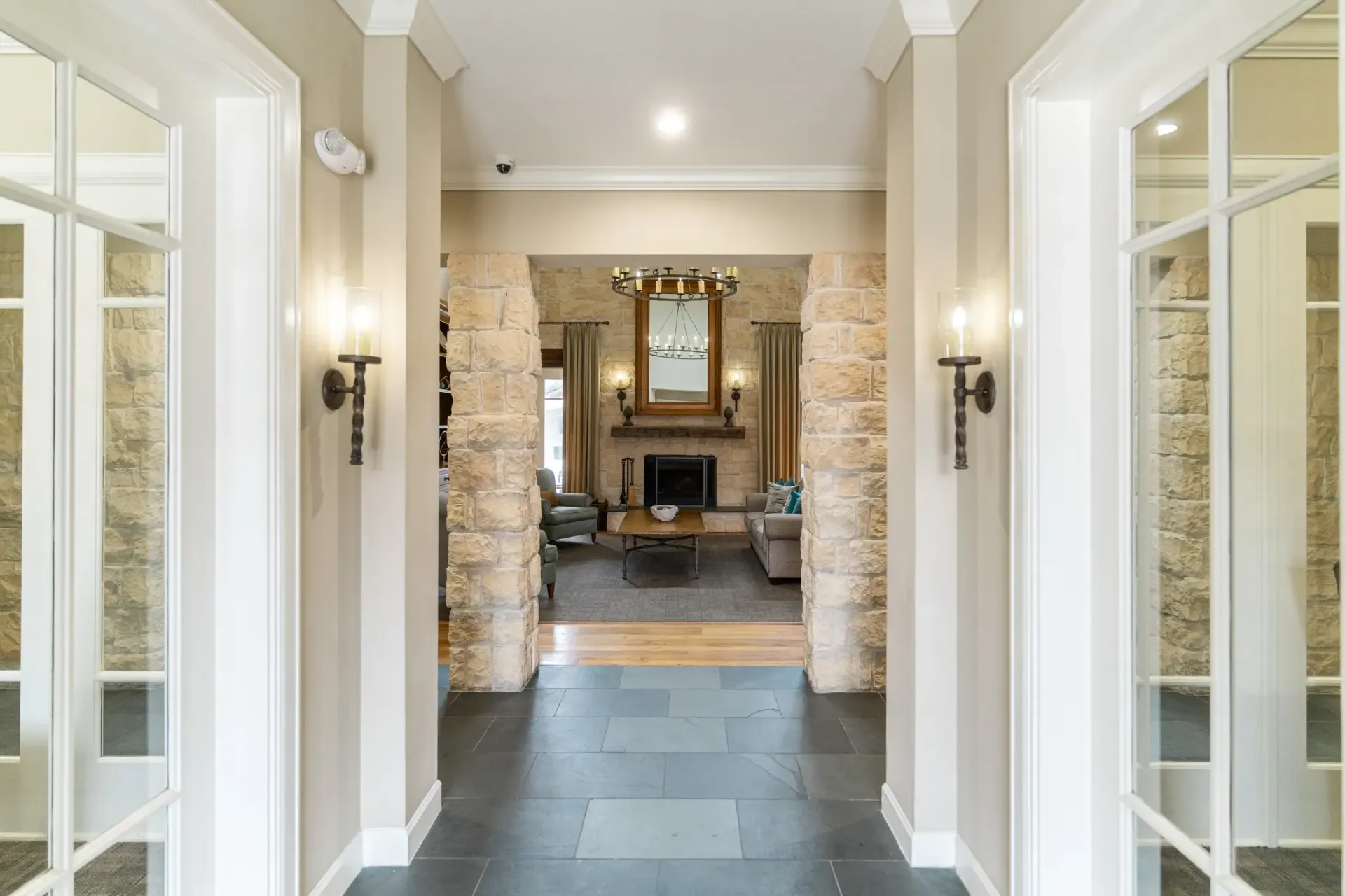 Hallway leading to a living room with stone accents, fireplace, and two sets of French doors.