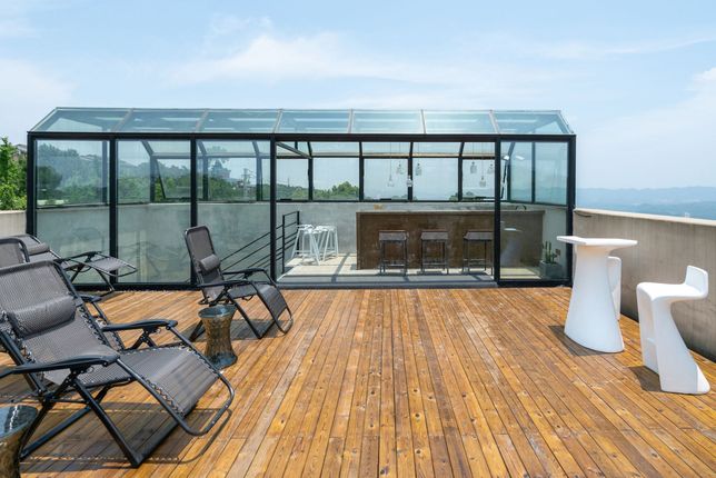 a wooden deck with chairs and tables on it and a glass roof .