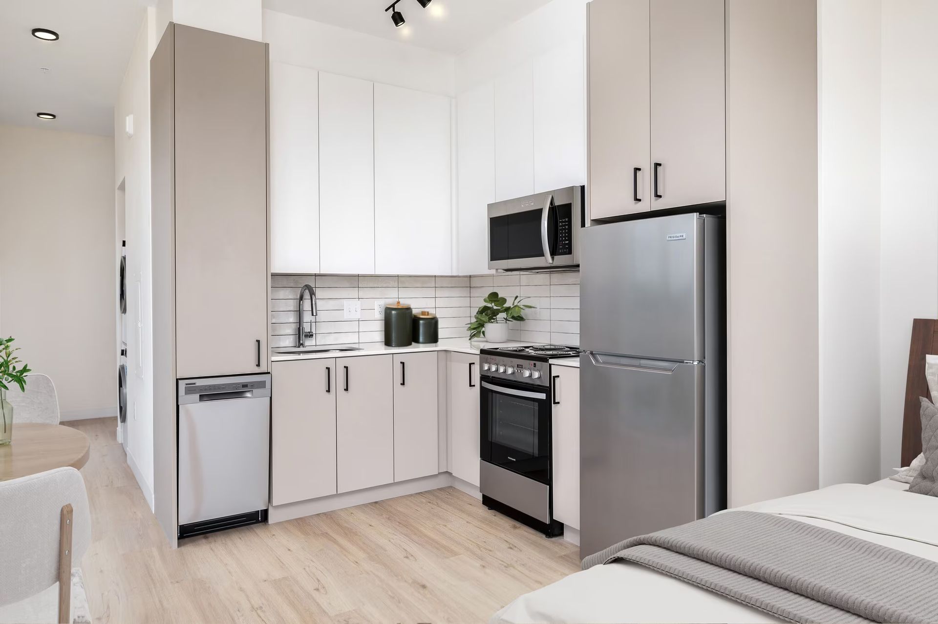 Small kitchen with white cabinets, stainless steel appliances, and a connected bedroom area.