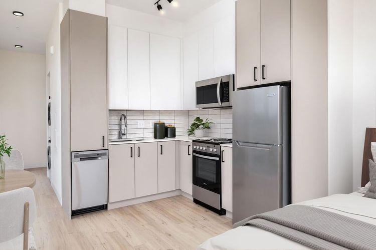 Small kitchen with white cabinets, stainless steel appliances, and a connected bedroom area.