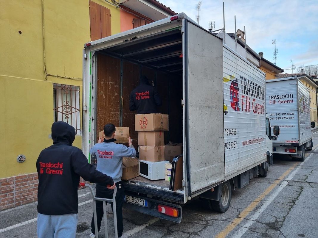 Operai scaricano scatole da un camion delle consegne in una strada stretta