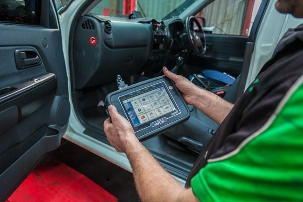 A Man in A Green Shirt Is Holding a Tablet — Envy Automotive in Gorokan, NSW