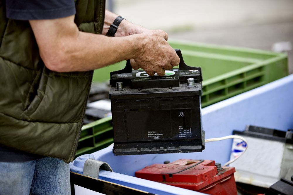 Man Holding a Black Car Battery — Envy Automotive in Budgewoi, NSW
