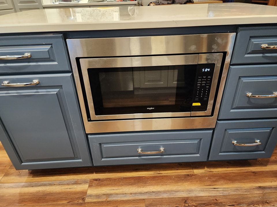 Built-in microwave oven in a blue kitchen cabinet. Stainless steel trim, black control panel.