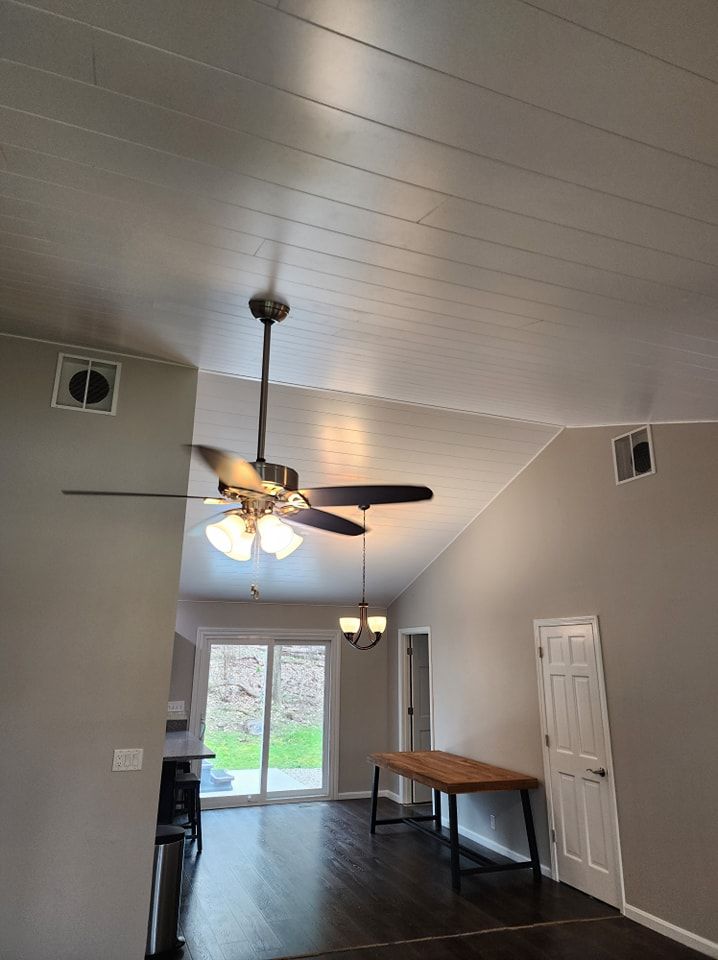 Interior view with high ceiling, ceiling fan, and dark wood floor. Dining table and glass door visible.