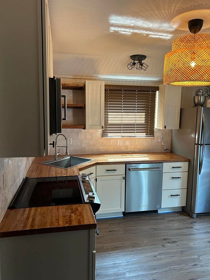 Kitchen with wooden countertops, white cabinets, stainless steel appliances, and a woven pendant light.