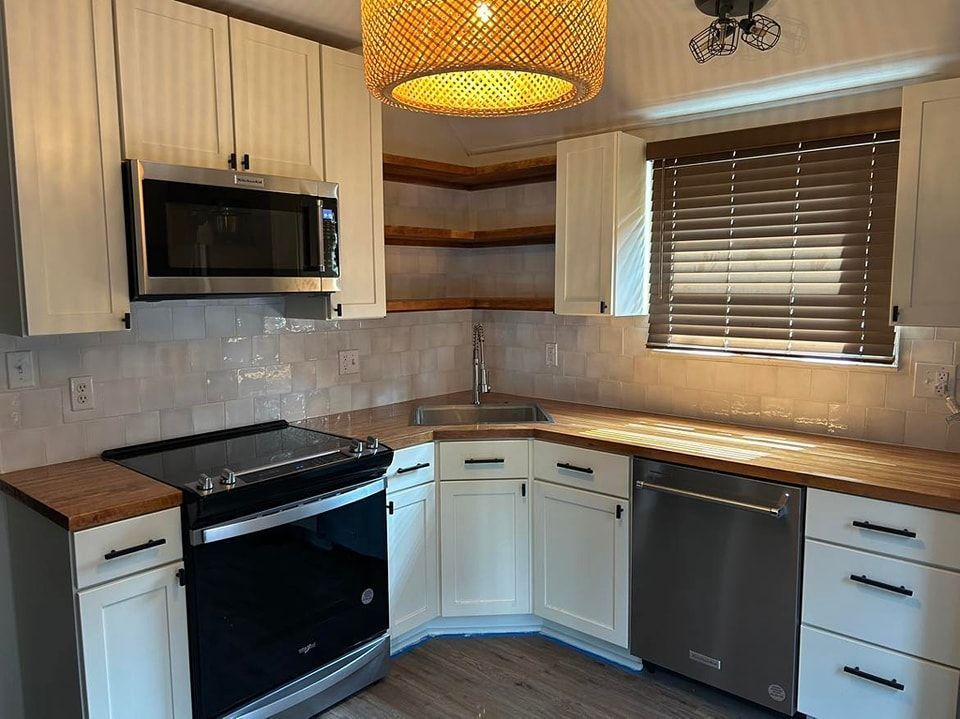 Kitchen with white cabinets, stainless steel appliances, and wood countertops.