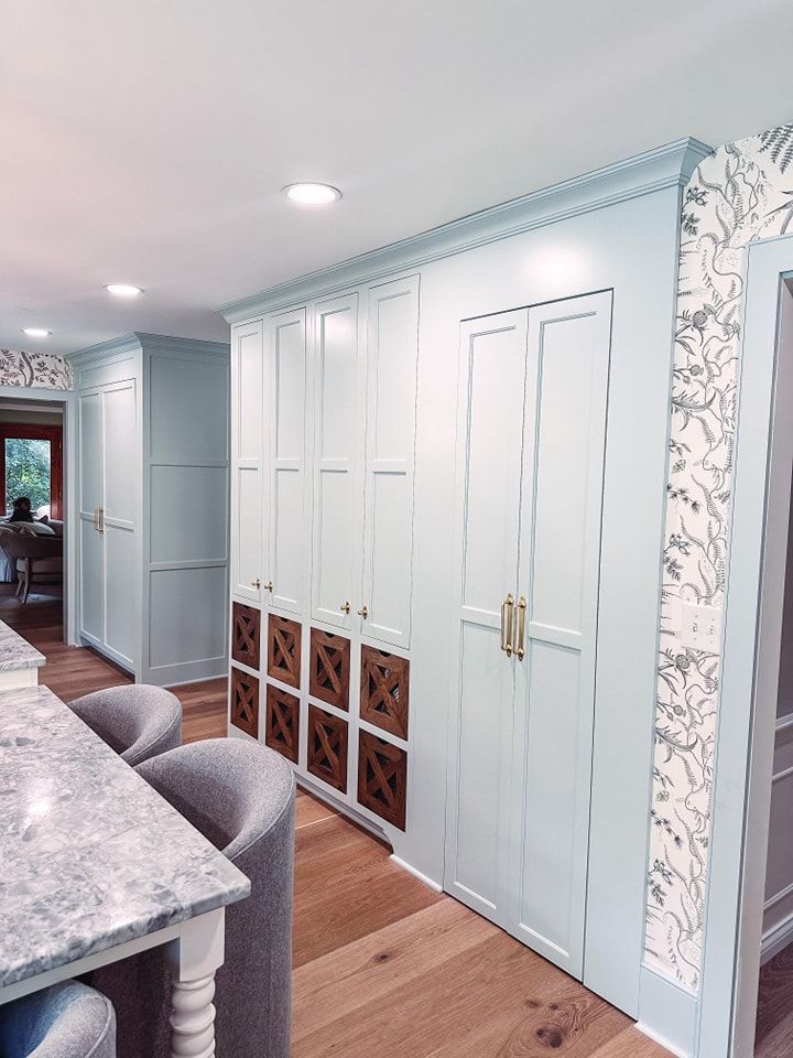 Light blue kitchen cabinets with wooden accents, and a marble countertop.