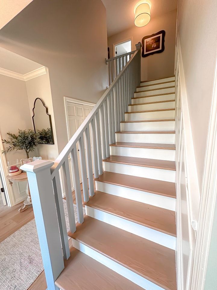 Staircase with light brown steps and painted light blue railing leading to a hallway.