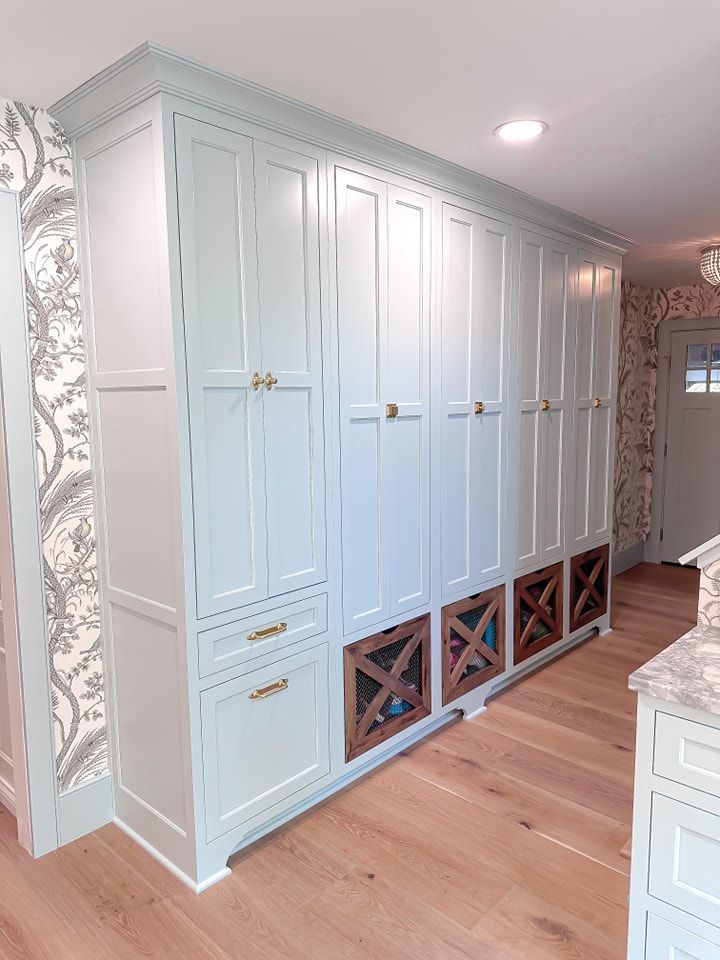 Light blue custom kitchen cabinetry with wooden wine racks and gold hardware.