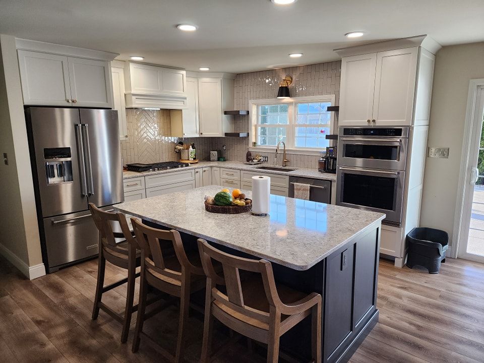 Modern kitchen with white cabinets, stainless steel appliances, and a dark island with seating.