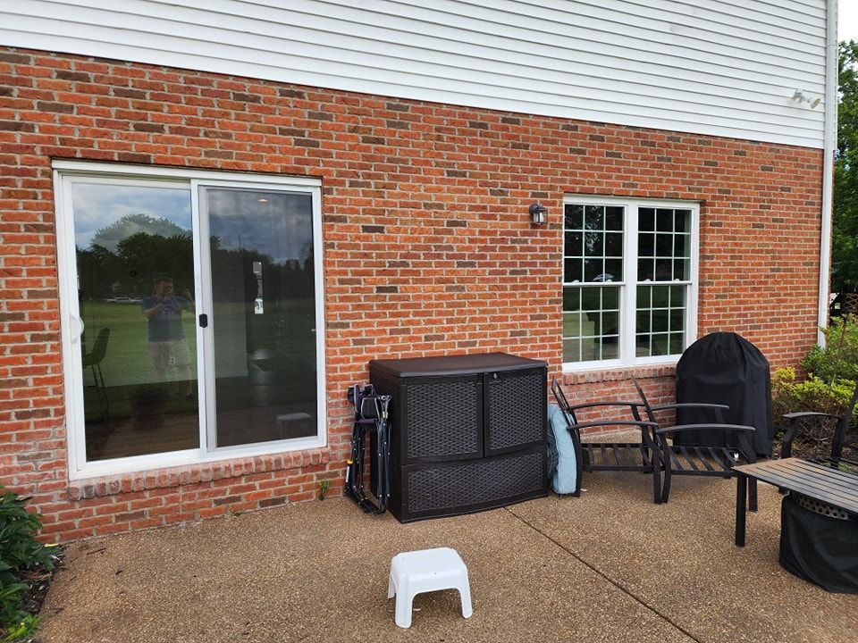 Brick house exterior with sliding glass door, window, patio, and storage box.