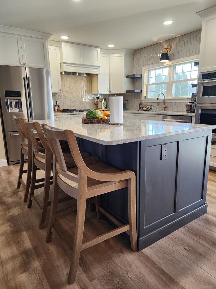 Kitchen with blue island, light countertops, wooden bar stools, and white cabinets.