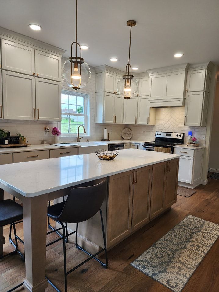 Modern kitchen with white cabinets, wood island, pendant lights, and hardwood floors.