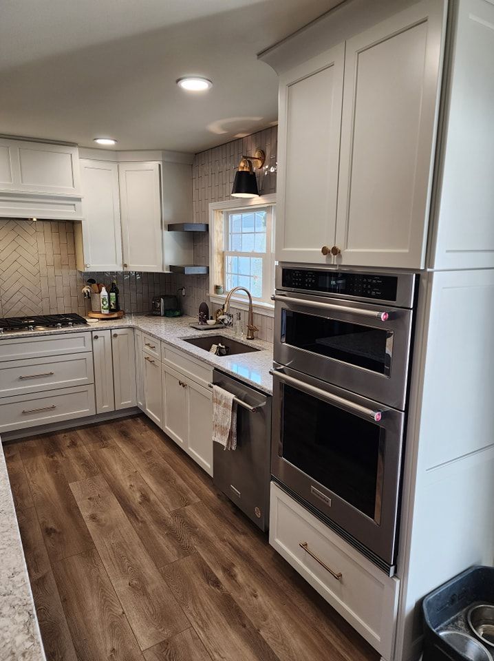 White kitchen cabinets with stainless steel appliances and wood-look flooring.