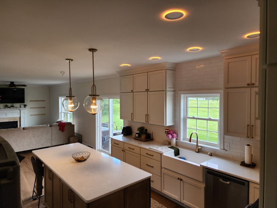 Modern kitchen with white cabinets, island, and pendant lights. Recessed ceiling lights.
