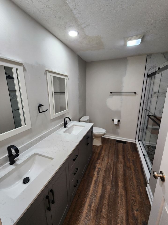 Bathroom with gray cabinets, white countertop, dark hardware, and wood-look flooring.