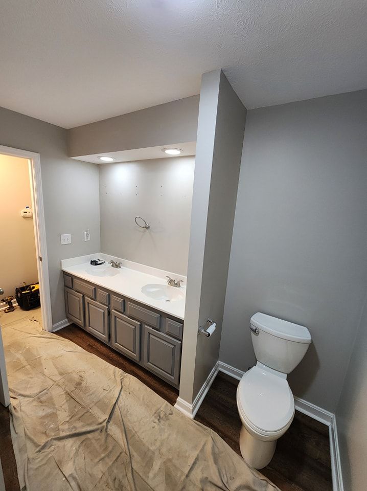 Bathroom renovation with gray cabinets, white countertop, and a toilet.