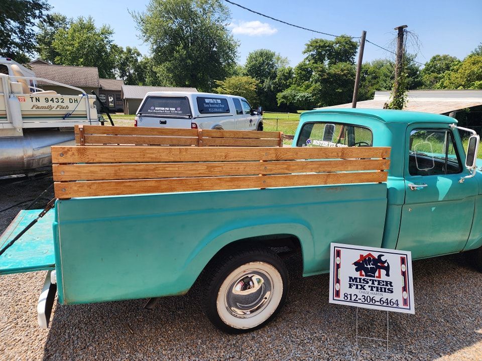 Teal pickup truck with wooden bed, white-wall tires, and a sign for 