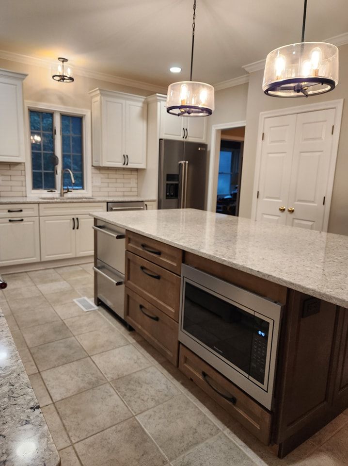 Kitchen with light-colored cabinets, stainless steel appliances, a wooden island, and two pendant lights.