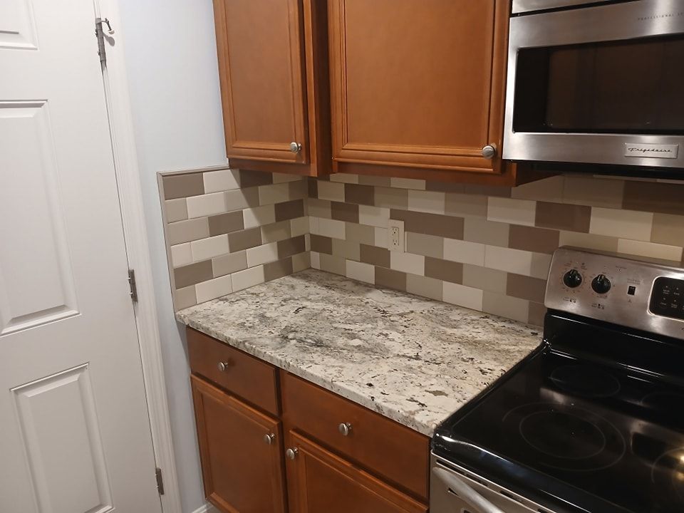 Kitchen counter with cabinets, backsplash, and appliances in earth tones.