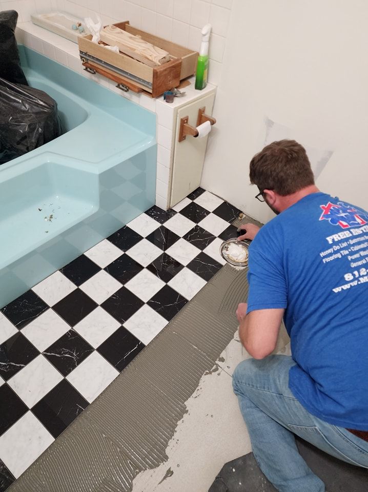 Man tiling a bathroom floor with a black and white checkerboard pattern.