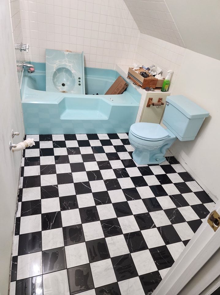 Bathroom with light blue tub and toilet, black and white checkered floor.