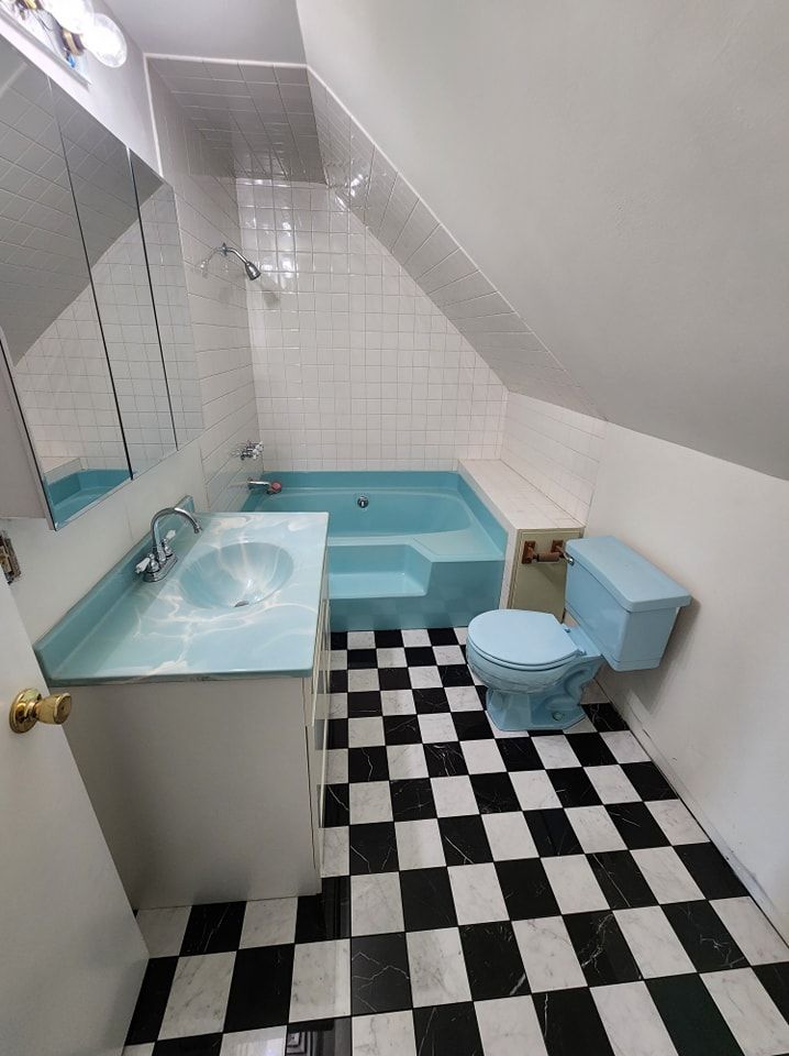 Bathroom with blue fixtures, white walls, and black and white checkered floor.