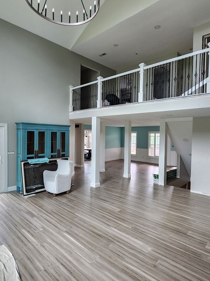 Spacious room with a loft and high ceilings. A blue cabinet and white armchair sit below the loft.