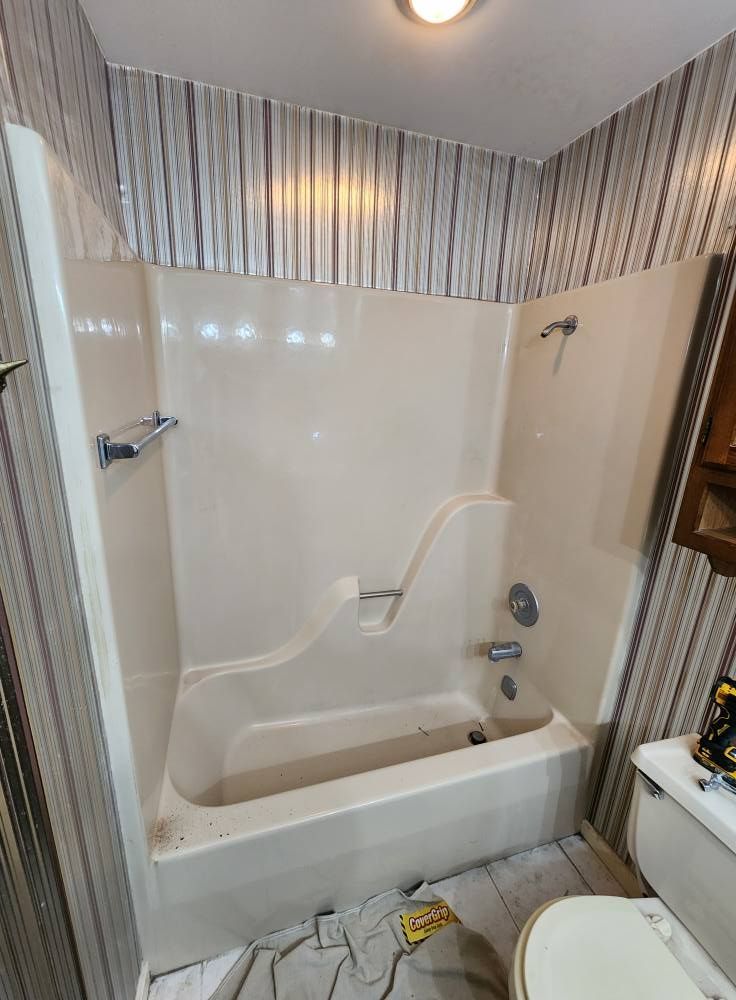 Bathroom with a white bathtub and beige walls with striped wallpaper.