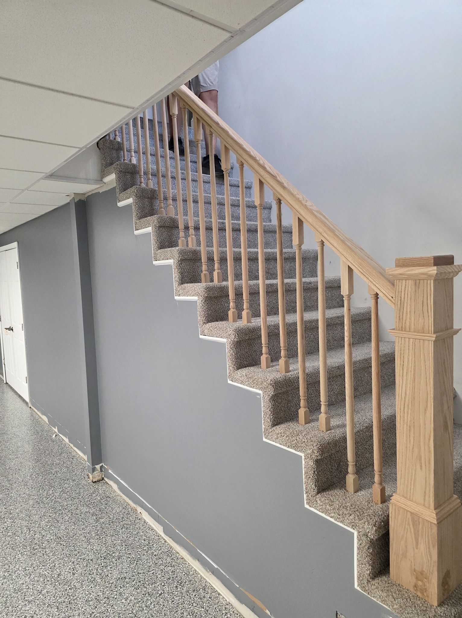 Staircase with carpeted steps, wooden handrail, and gray walls.